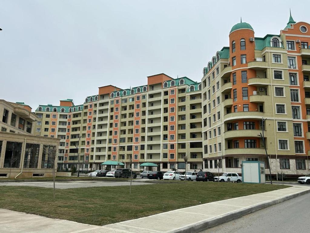 ein großes Apartmenthaus mit Autos auf einem Parkplatz in der Unterkunft Mirvari in Sumqayıt