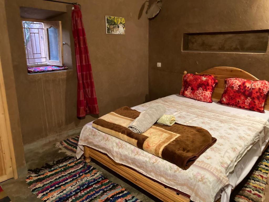 a bedroom with a large bed with red pillows at Authentic riad & activities Erg in Mhamid