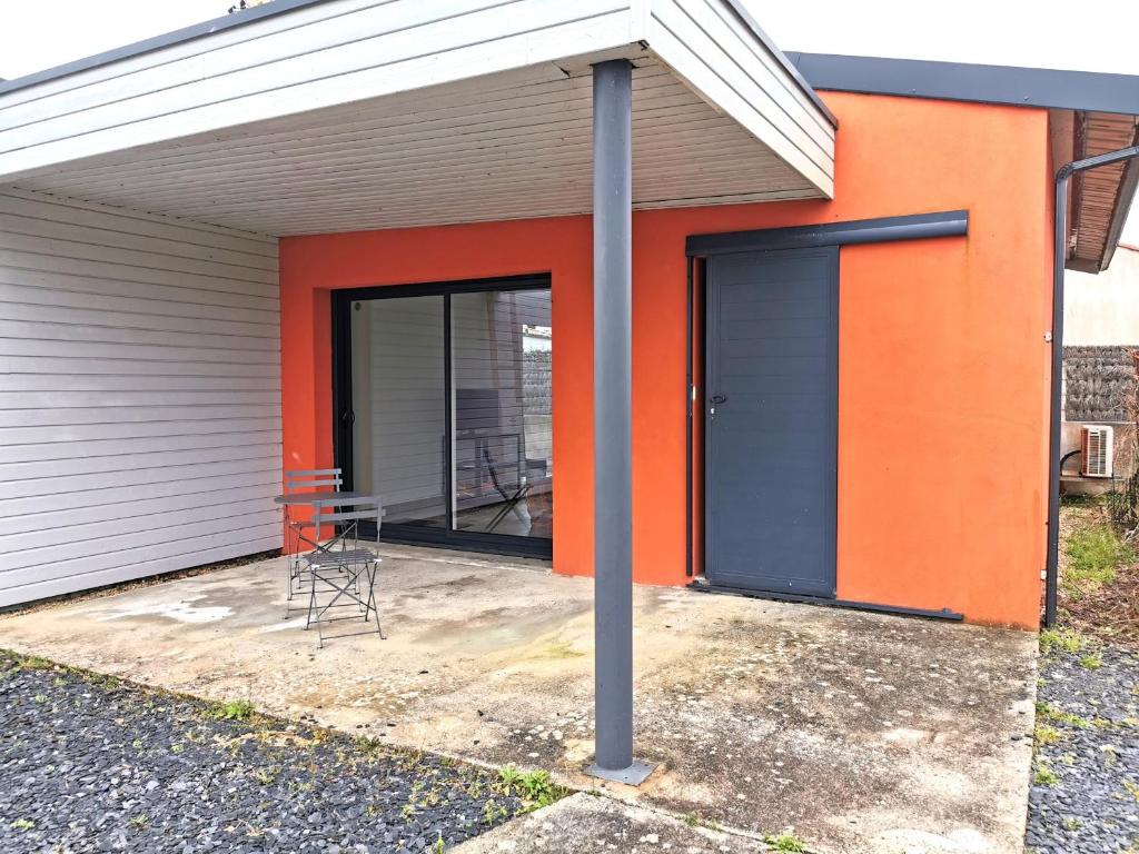 een gebouw met een oranje en zwarte deur en een stoel bij Case Couleur proche de la mer in Brem-Sur-Mer