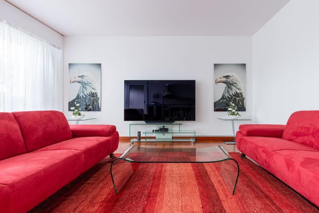 een woonkamer met rode banken en een flatscreen-tv bij Perle rare nations in Genève
