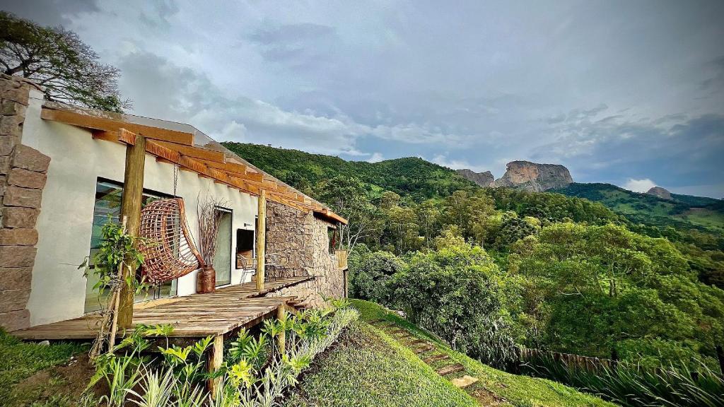 una casa con un portico in legno e montagne sullo sfondo di Cabana Rinoceronte a São Bento do Sapucaí