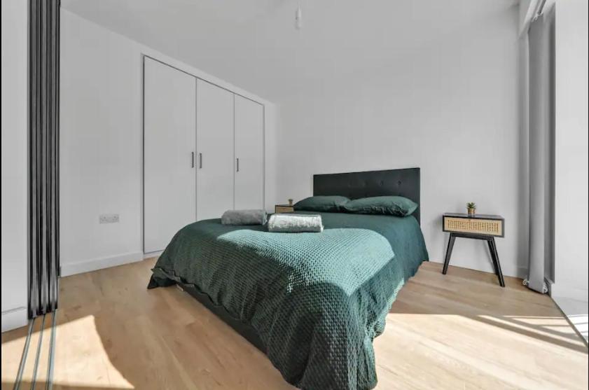 um quarto com uma cama com um cobertor verde em Colindale NW9 1BED TV/WIFI em Colindale