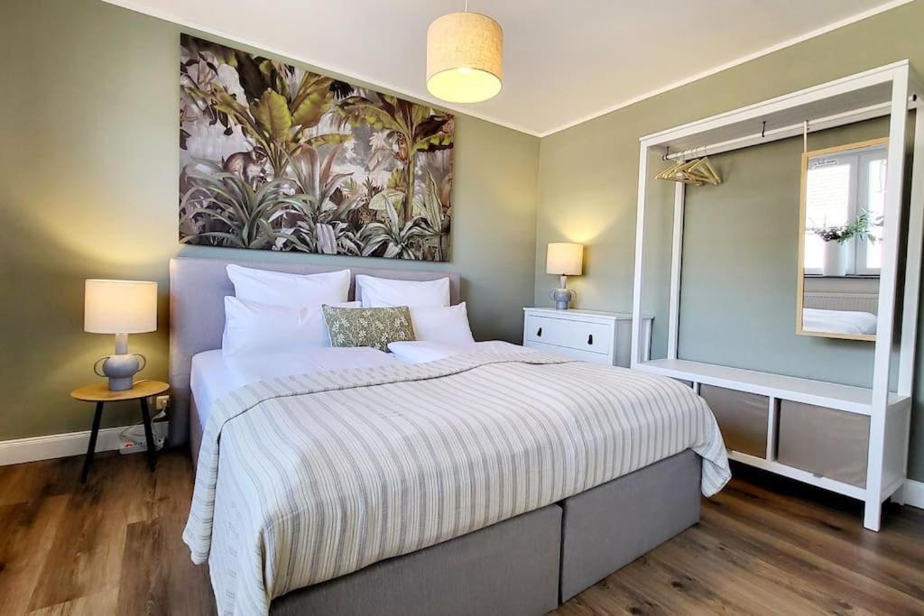 a bedroom with a large bed with a painting on the wall at JOOYFUL STAYS Townhouse in Kevelaer