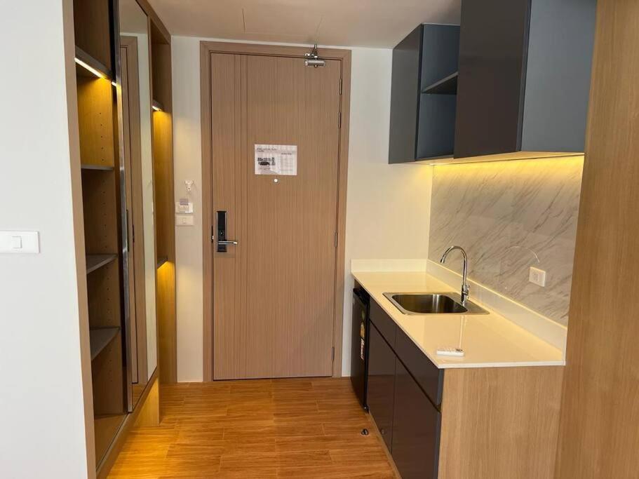 eine Küche mit einem Waschbecken und eine Tür zu einem Flur in der Unterkunft Sea Beach apartment in Nai Thon Beach