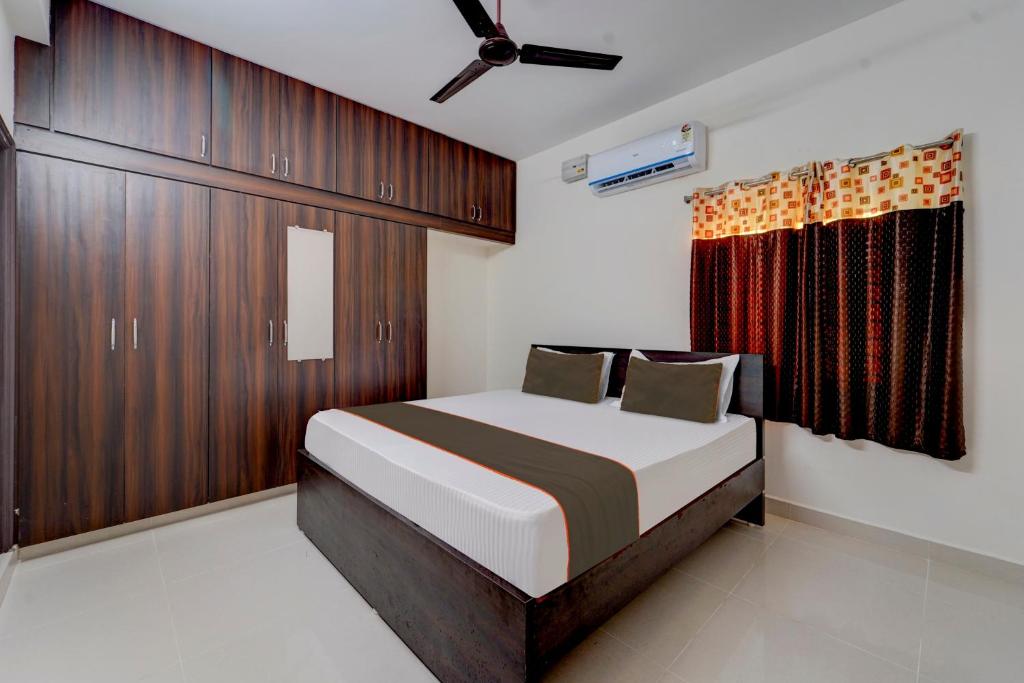 a bedroom with a bed with wooden cabinets and a window at Collection O New Balaji Homestay in Tirupati