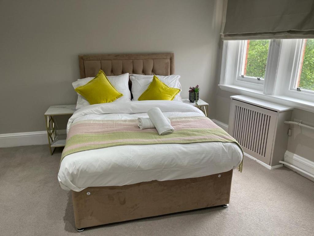 a bedroom with a large bed with yellow pillows at Falcon suits in London