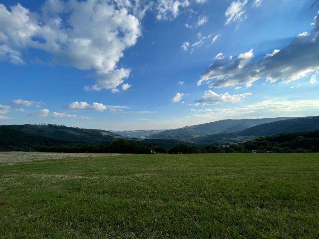 a field with a blue sky and mountains in the background at Nádherné místo pro váš relax v přírodě in Uherské Hradiště