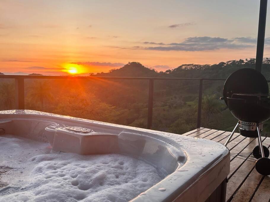 einen Whirlpool auf einer Terrasse mit Blick auf den Sonnenuntergang im Hintergrund in der Unterkunft GoldenView+ Aire acondicionado+Jacuzzi (a 15 km de Monteverde) in Monteverde Costa Rica