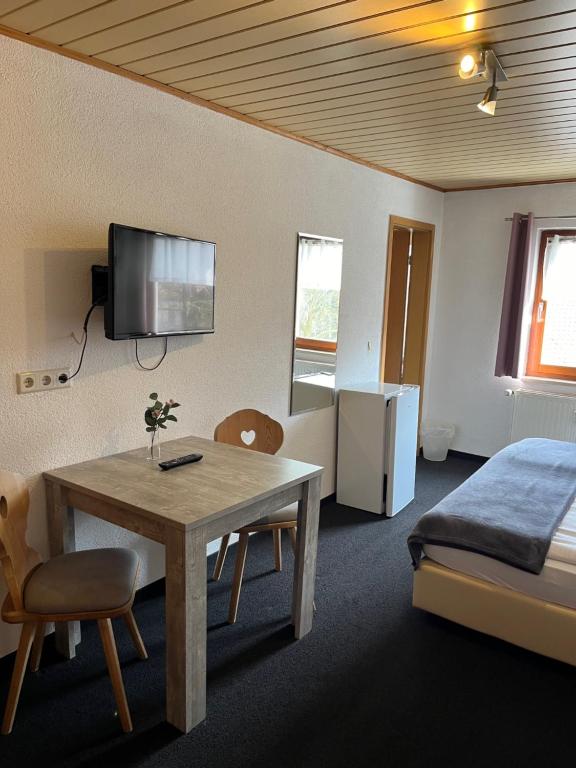 a hotel room with a table and a bed and a television at Pension Unterreichenbach in Schwabach