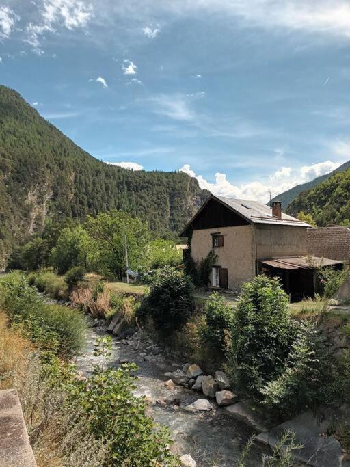 une maison dans les montagnes avec un ruisseau devant dans l'établissement Maison de montagne 2 à 8 couchages proche Barcelonette, à Condamine-Châtelard