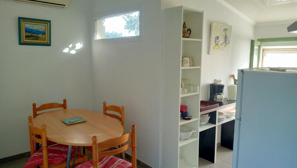 einen kleinen Tisch und Stühle in einer Küche mit Kühlschrank in der Unterkunft Gîte 3 pièces dans Mas Catalan proche centre ville in Perpignan