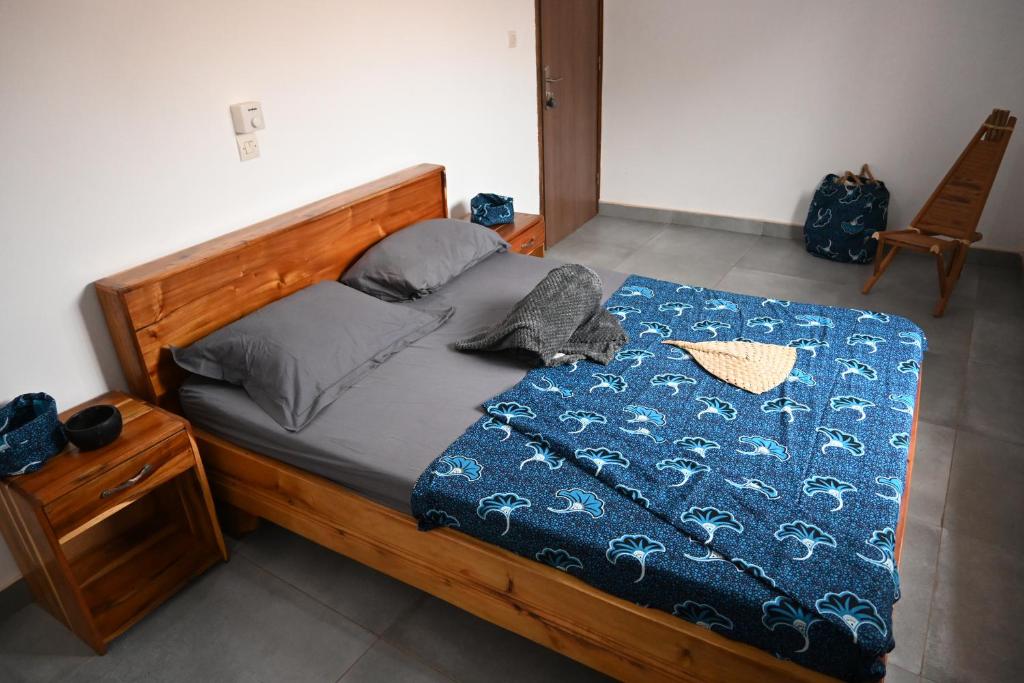 a bedroom with a wooden bed with a blue comforter at Les Amazones Rouges Chambre Bleue in Ouidah