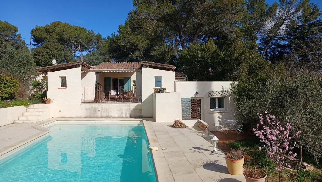 a villa with a swimming pool in front of a house at Charmant petit studio avec jardin et piscine in Nîmes