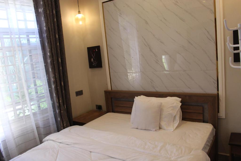 a bedroom with a bed with white sheets and a window at ISN Luxury Apartments in Dodoma