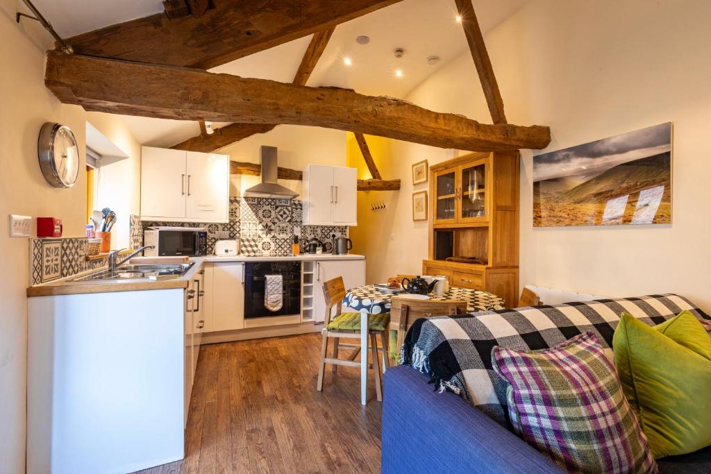 a kitchen and a living room with a blue couch at Dragonfly Cottage, Canal location in Brecon