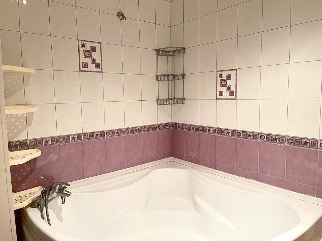 uma banheira na casa de banho com azulejos roxos e brancos em Набережная 2 кв Центр города ЖД em Dnipro
