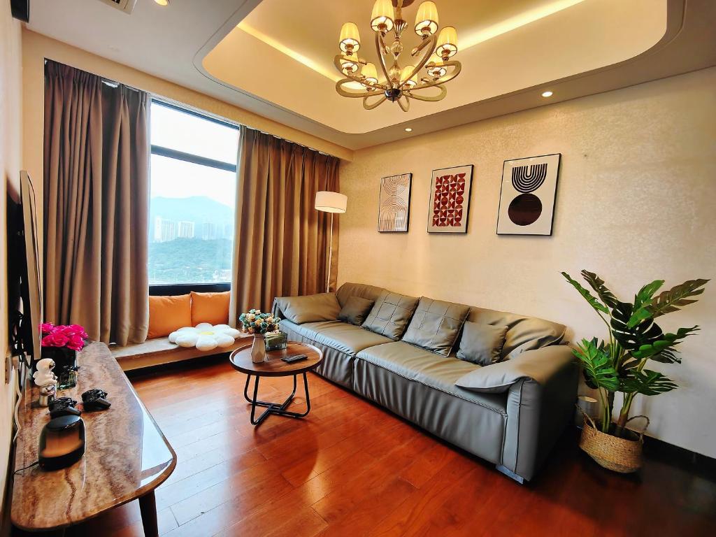 a living room with a couch and a large window at Mangrove Bay Riverside Hill Riverview B&Bl紅樹灣河畔山河景民宿l毗邻澳門l拱北l華發商都 in Zhuhai