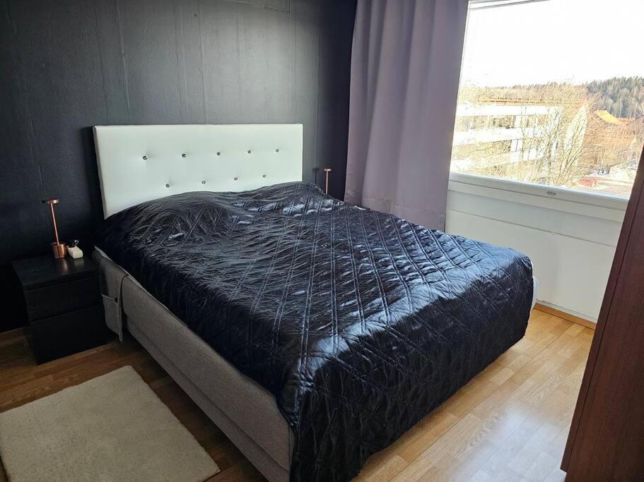 - une chambre avec un lit doté d'une couette noire et d'une fenêtre dans l'établissement Miller Apartment - Free parking, airport 21min, à Klaukkala