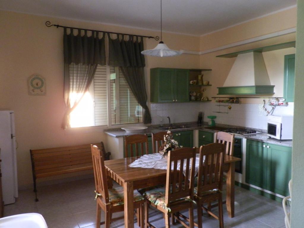 een keuken met een tafel en stoelen en een keuken met groene kasten bij Casa del Capitano in Villasimius