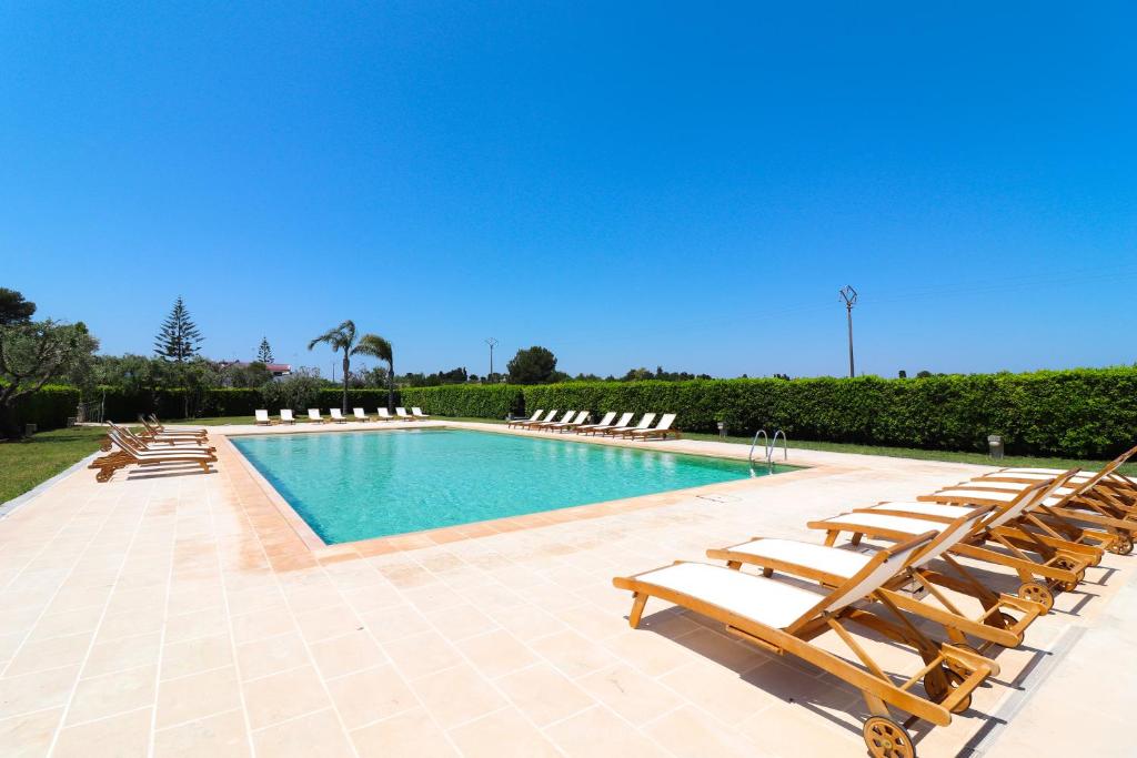 una piscina con sedie a sdraio e un mucchio di cose di Casa Aleatico Residence Torre Santo Stefano in Otranto ad Alimini