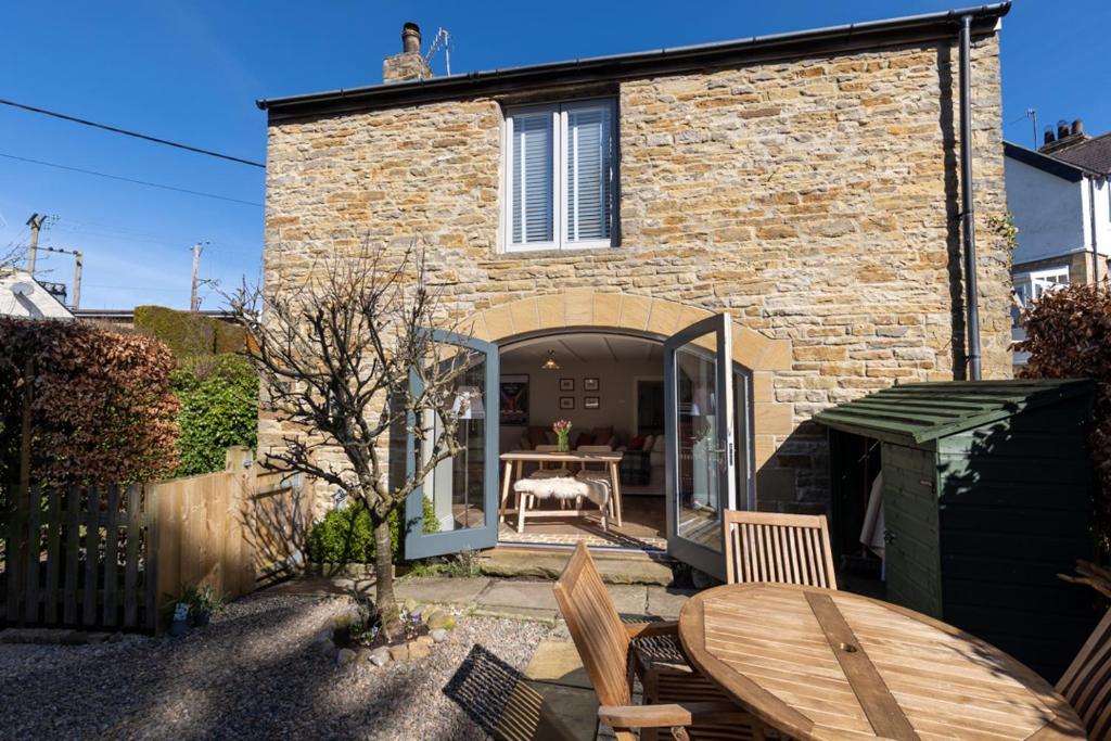 a patio with a table and chairs in front of a building at Dene Croft Cottage in Hexham