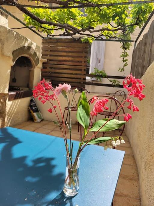 un vase avec des fleurs roses assises sur une table dans l'établissement Maison In Vino, à Nyons