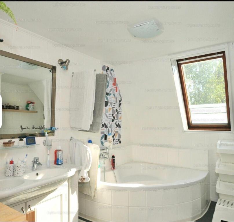 La salle de bains blanche est pourvue d'une baignoire et d'un lavabo. dans l'établissement Klebi’s Apartmanház 20, à Balatonföldvár