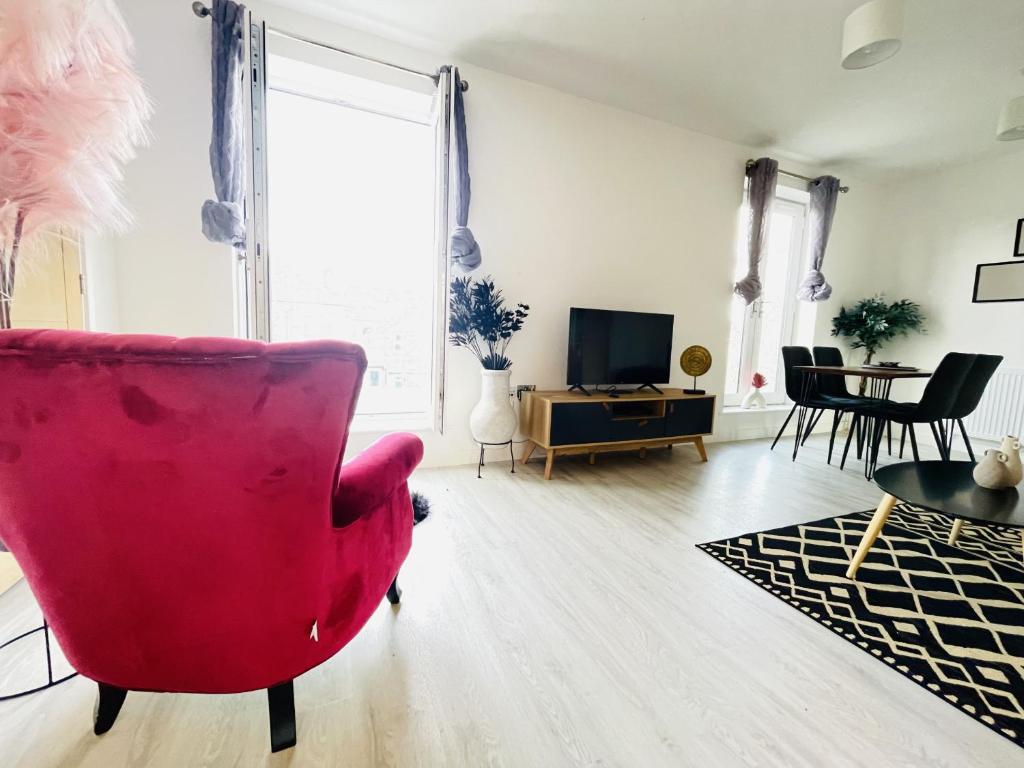 uma sala de estar com uma cadeira vermelha e uma mesa em Spacious 4 Bedroom, Wi-Fi, 2 Gardens, Sleeps 8 - Amethyst em Cambridge
