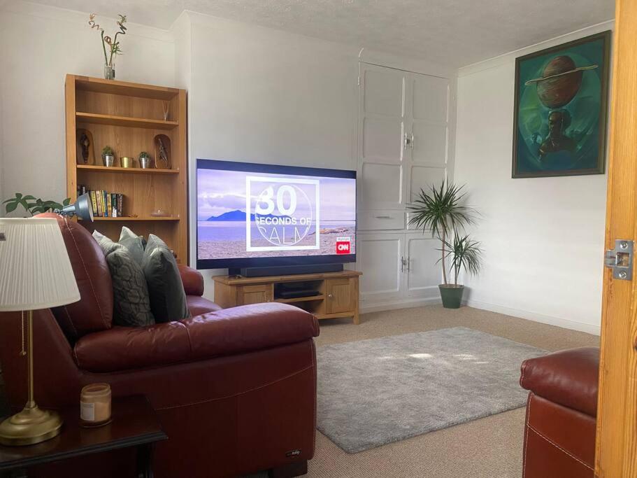 een woonkamer met een bank en een flatscreen-tv bij A secured 3 bedroom family home in Radcliffe