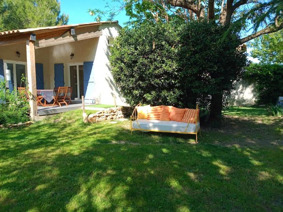 un canapé assis dans l'herbe devant une maison dans l'établissement Villa avec piscine dans un avre de verdure, à Caderousse