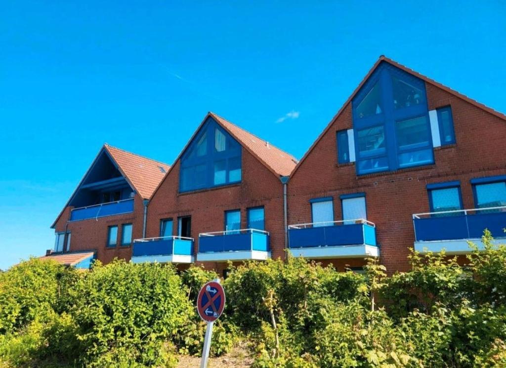 Watt´ne Bude in Büsum في بوسوم: مبنى من الطوب الأحمر مع نوافذ زرقاء وعلامة على الشارع