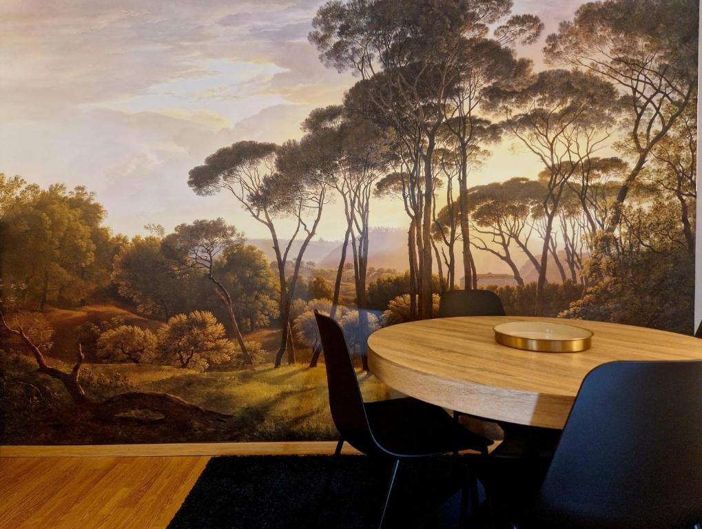 a dining room with a painting of a forest at Chez Valérian, gare de Chantilly in Chantilly