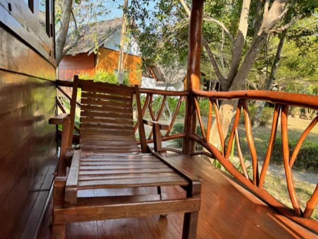 un banc en bois assis sur une terrasse en bois dans l'établissement Baan rabiang Pai บ้านระเบียงปาย, à Pai