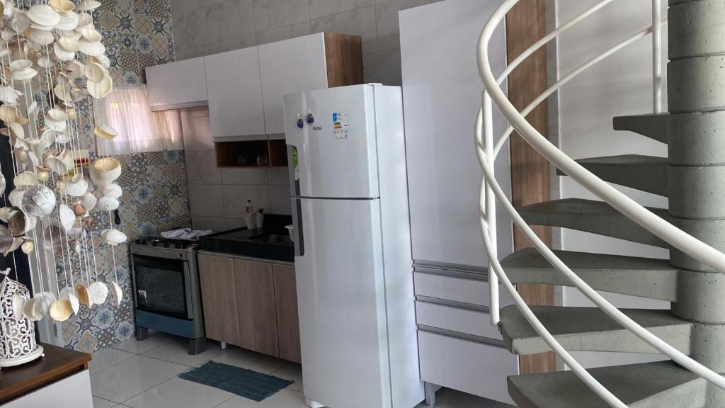 a kitchen with a white refrigerator and a spiral staircase at Mandakaru Residence Flat da Isa 01 in Porto De Galinhas