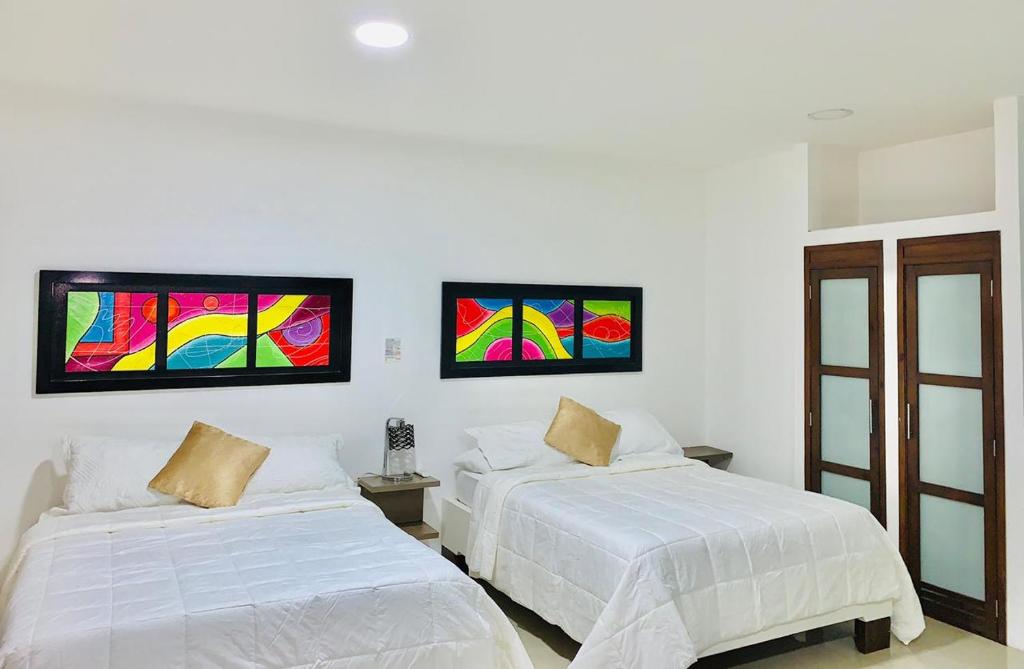 um quarto com duas camas e pinturas na parede em Apartahotel Bahia Tropical II em San Andrés