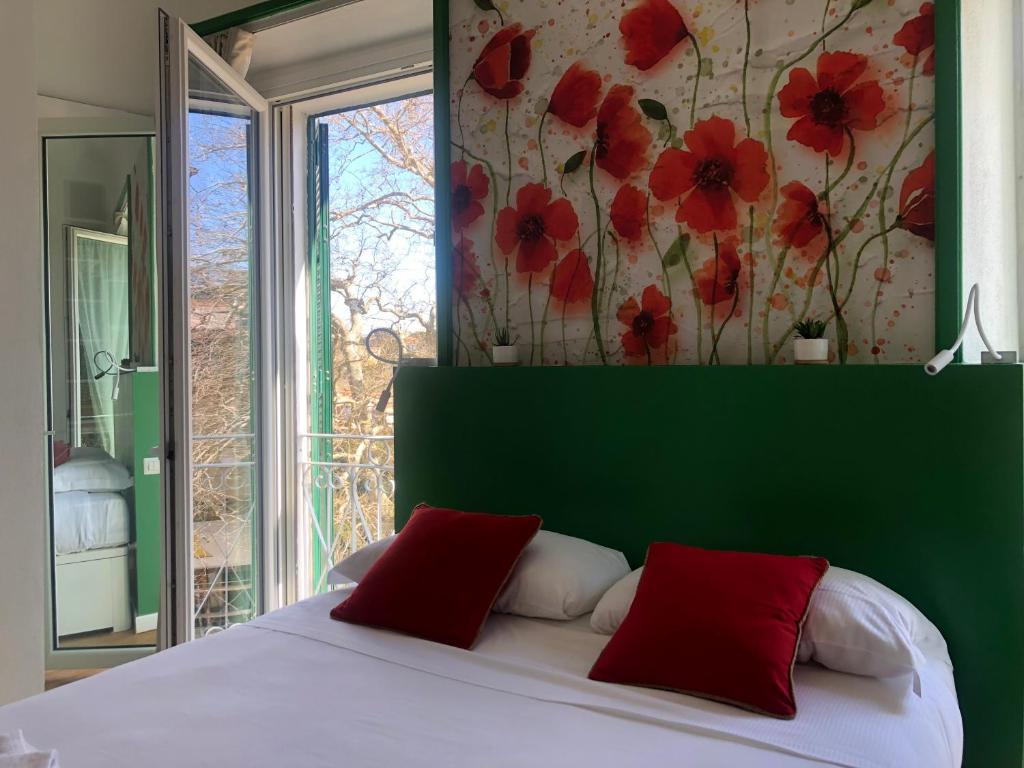 1 dormitorio con 1 cama con cabecero verde y ventana en DIMOR'A' ROOMS, en Pitigliano