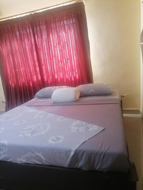 a bed with a red headboard with two pillows at Cee's apartment in Chipata