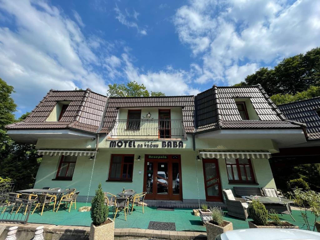 a building with a balcony and tables and chairs at Motel na vrchu Baba s.r.o. in Pezinok