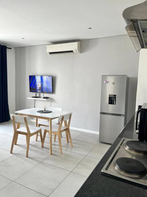 una cucina con tavolo, sedie e frigorifero di DMN City Junction Apartment a Windhoek