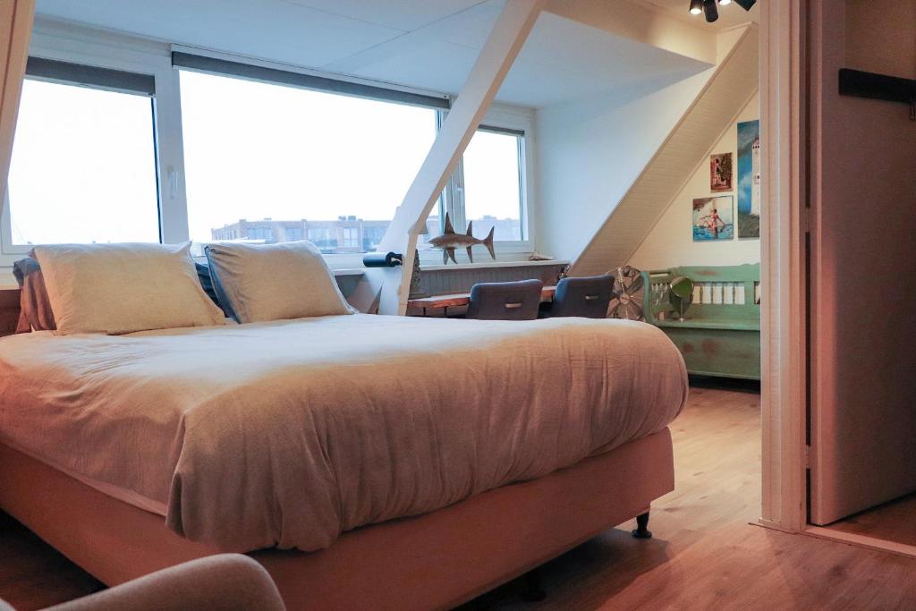a bedroom with a large bed in front of windows at B&B Zee-en-Zo in Noordwijk