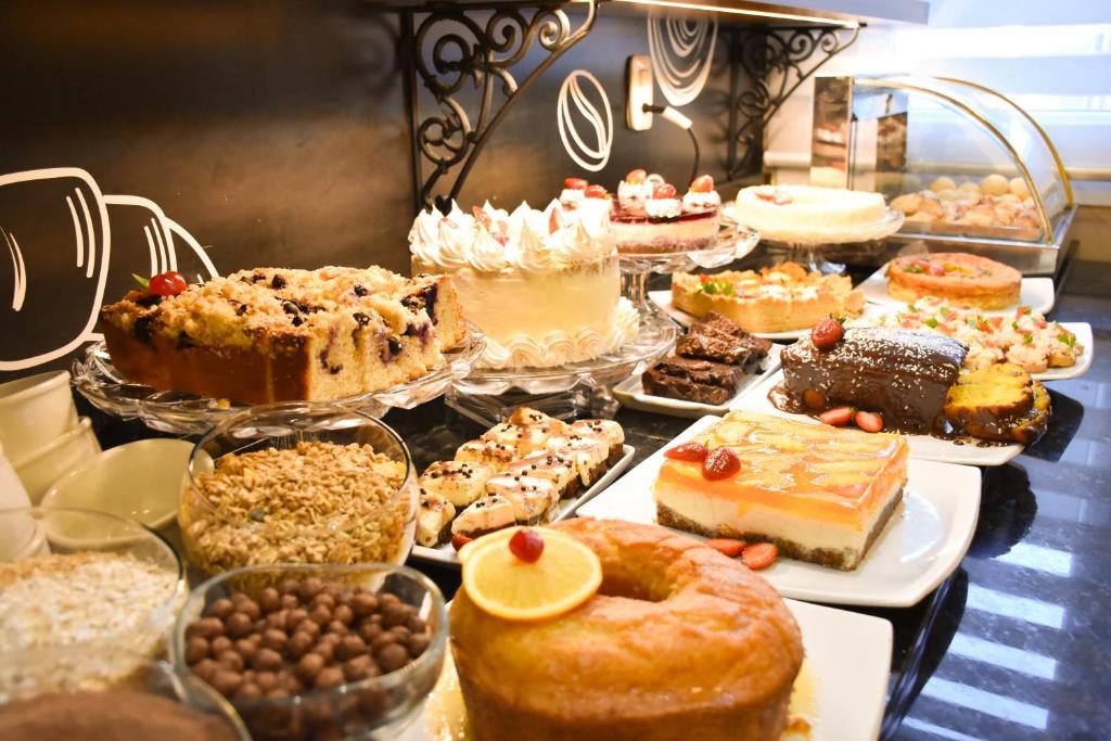 una mesa llena de diferentes tipos de pasteles y repostería en Pousada Stillo Gramado Exclusive, en Gramado