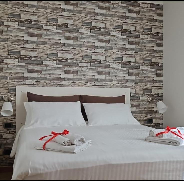 1 dormitorio con cama blanca y pared de ladrillo en Casa vacanze Valemì, en Zagarolo