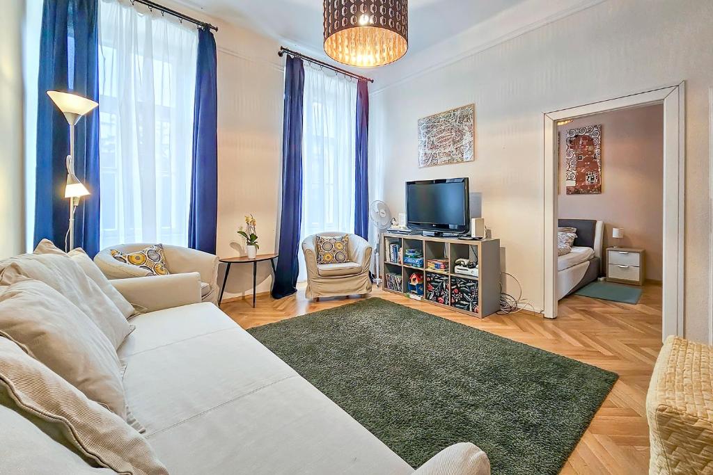 a living room with a white couch and a tv at Széchenyi Apartment Sopron in Sopron