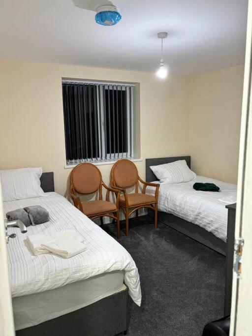 マンチェスターにあるStunning 2 bed rear flat Manchesterのベッド2台と椅子2脚が備わる客室です。