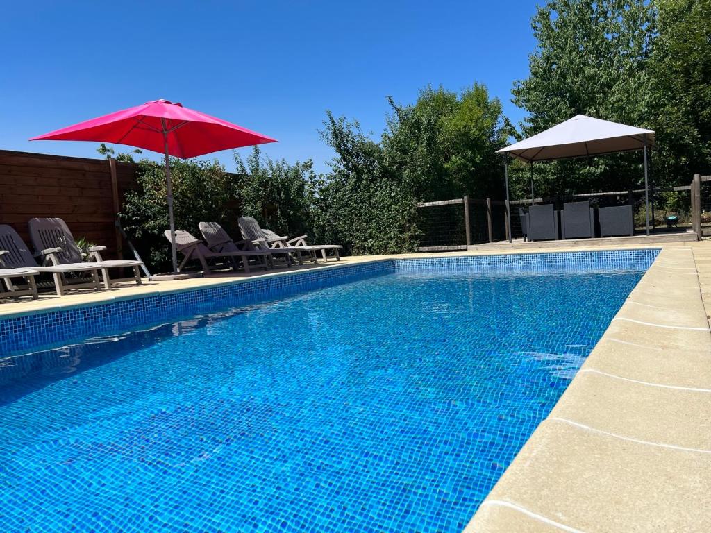 a swimming pool with a red umbrella and some chairs and a red umbrella at Les Cerisiers in Chaunay