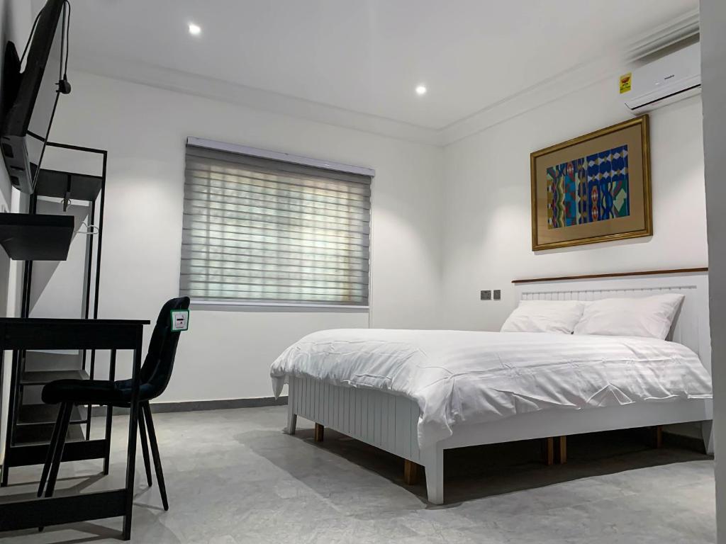 - une chambre blanche avec un lit et une chaise dans l'établissement Cony’s Guest House, à Kwabenyan