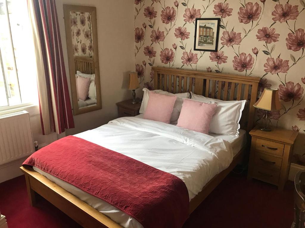 um quarto com uma cama grande e almofadas cor-de-rosa em The Apple House em York