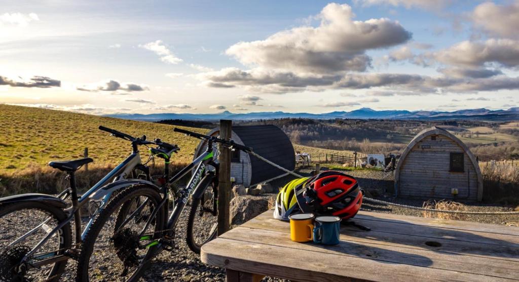 a bike parked on a wooden table with a backpack at The Arns Glamping Pods in Bridge of Allan