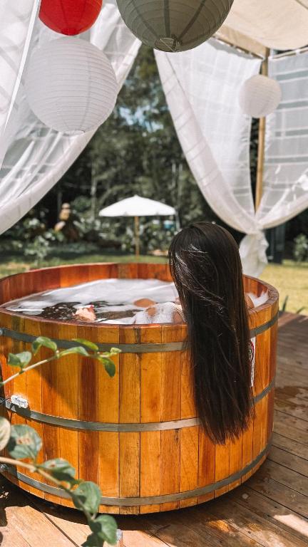a woman sitting in a wooden tub with her hair at Ônibus Oriental com Ofurô - Domingos Martins ES in Domingos Martins