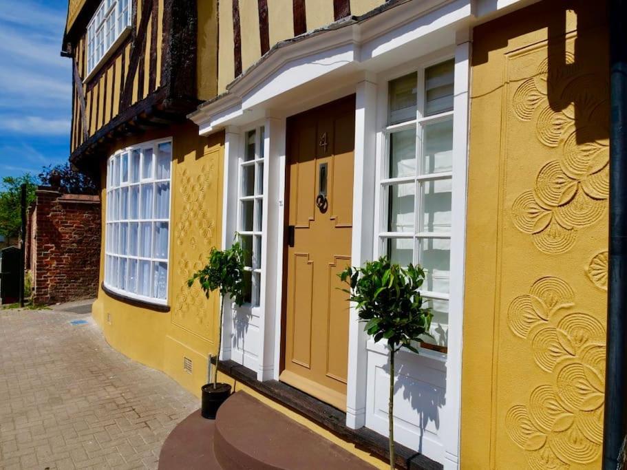un edificio amarillo con una puerta y ventanas amarillas en Versace 2 Bed Manor House With Hot Tub, en Saffron Walden